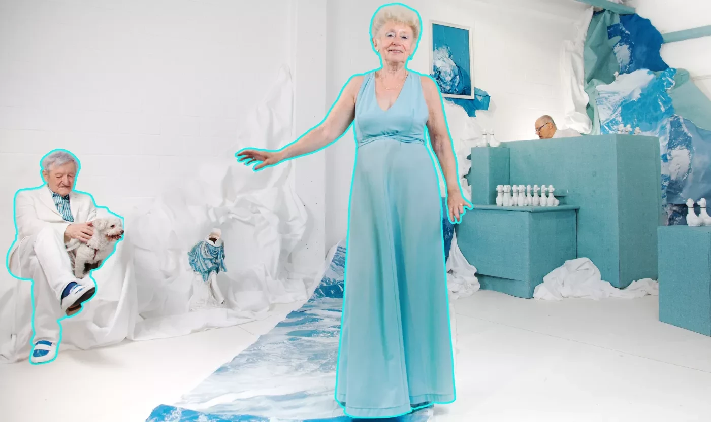 Femme âgée en robe turquoise dans un décor blanc et bleu; homme assis avec un chien, arrière-plan artistique.